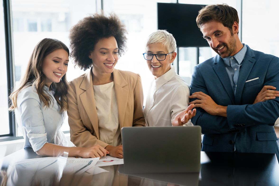 People stand around a laptop