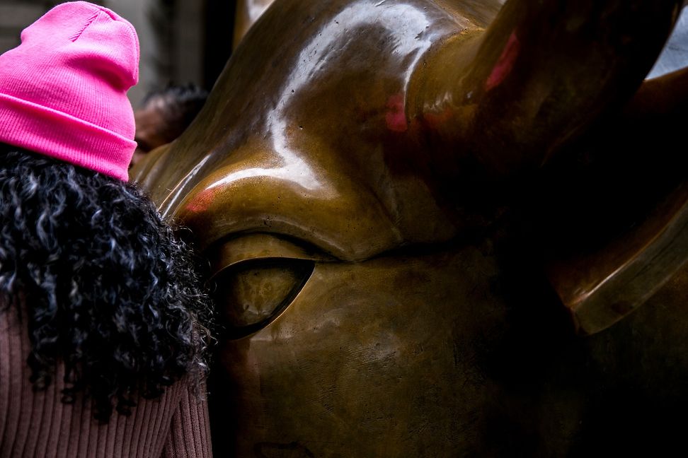 Close-up of a statue of a bull with a person passing by