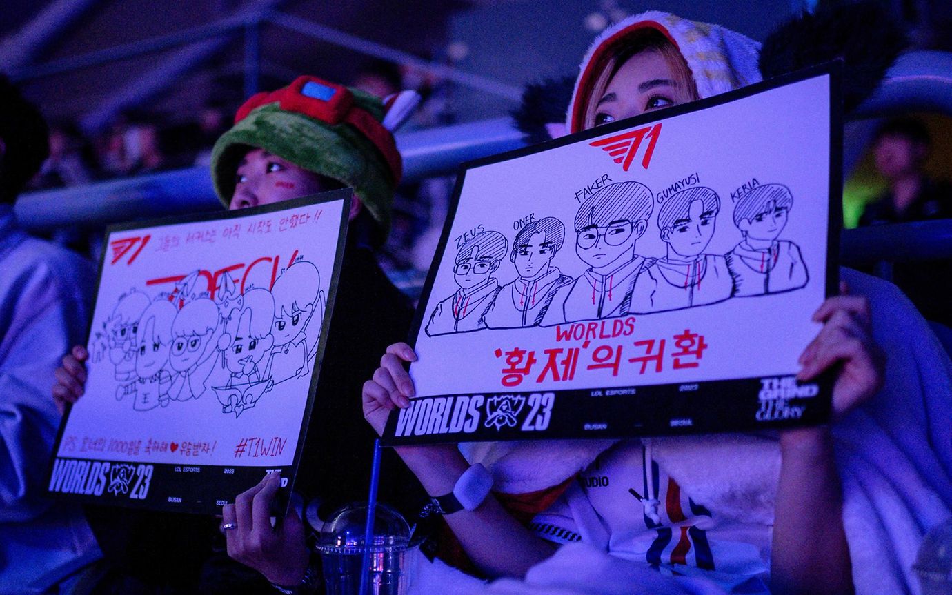 Two fans in a stadium holding up posters for their team