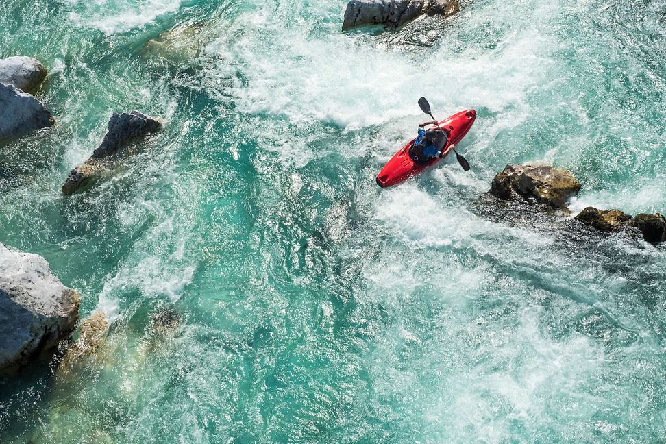 rotes Kajak über Steine und Wildwasser, aus der Vogelperspektive gesehen