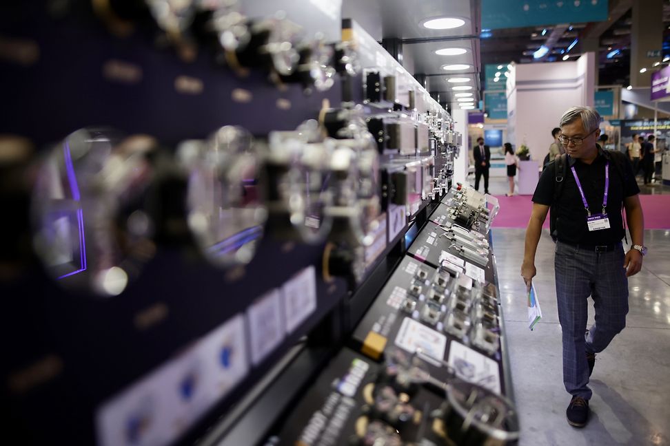 A man with a visitor's pass on a lanyard looks at technology at a trade fair