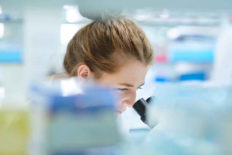 A female scientist looking through a microscope