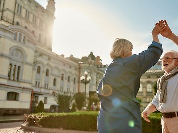 Man and woman, both senior citizens, dancing in a park