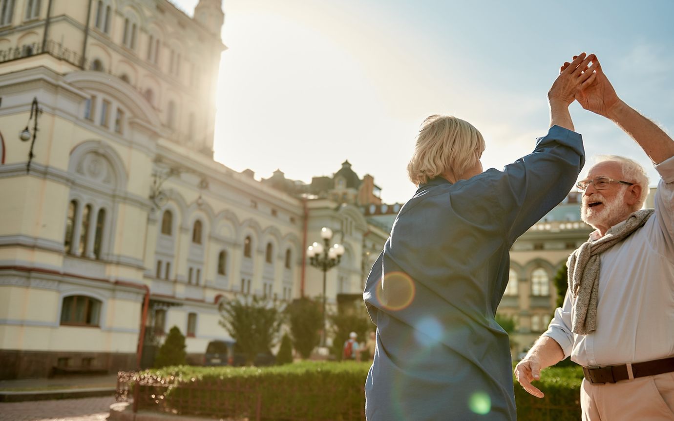 Man and woman, both senior citizens, dancing in a park