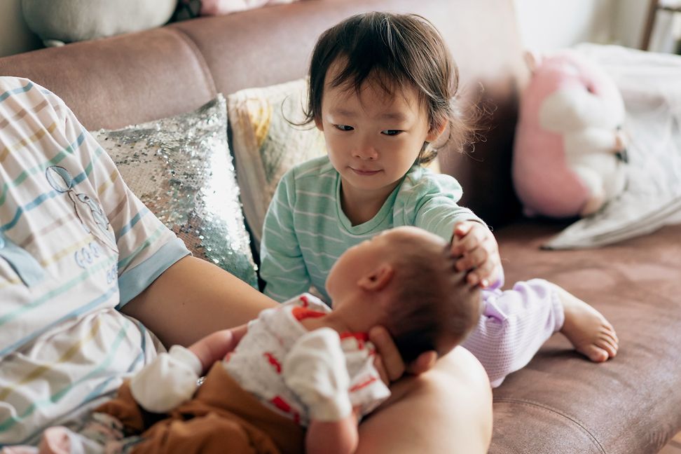 A toddler greets his newborn sibling