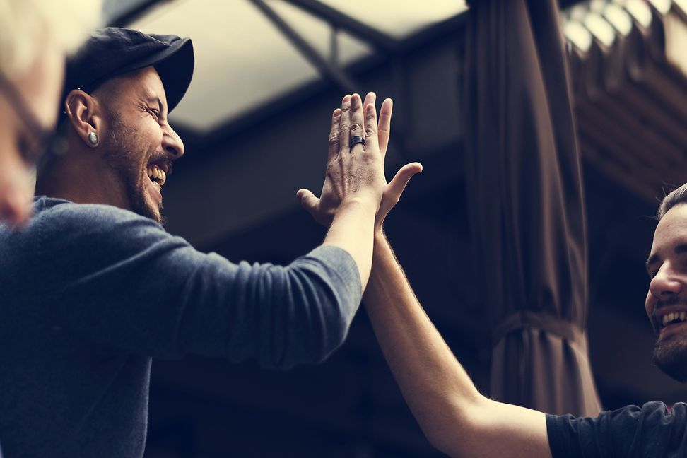 Two happy men in a work environment giving each other a high five. 