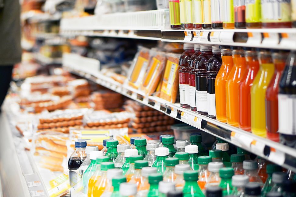 A supermarket shelf with drinks bottles and packaged consumer goods.