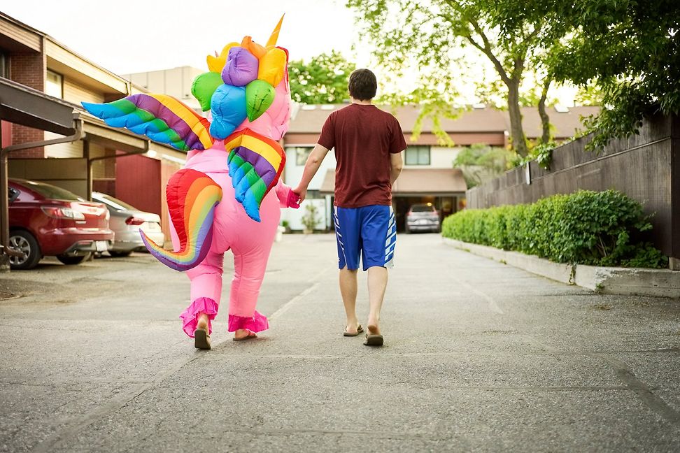 Two people are walking from behind, hand in hand, along a street in a quiet residential area.