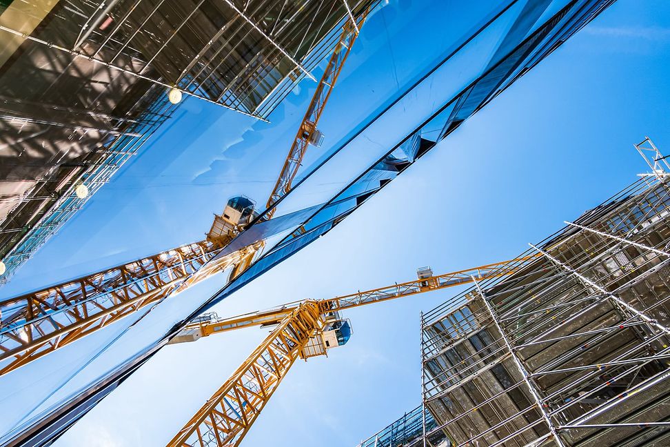 From below you can see a modern crane on a building site against the sky.