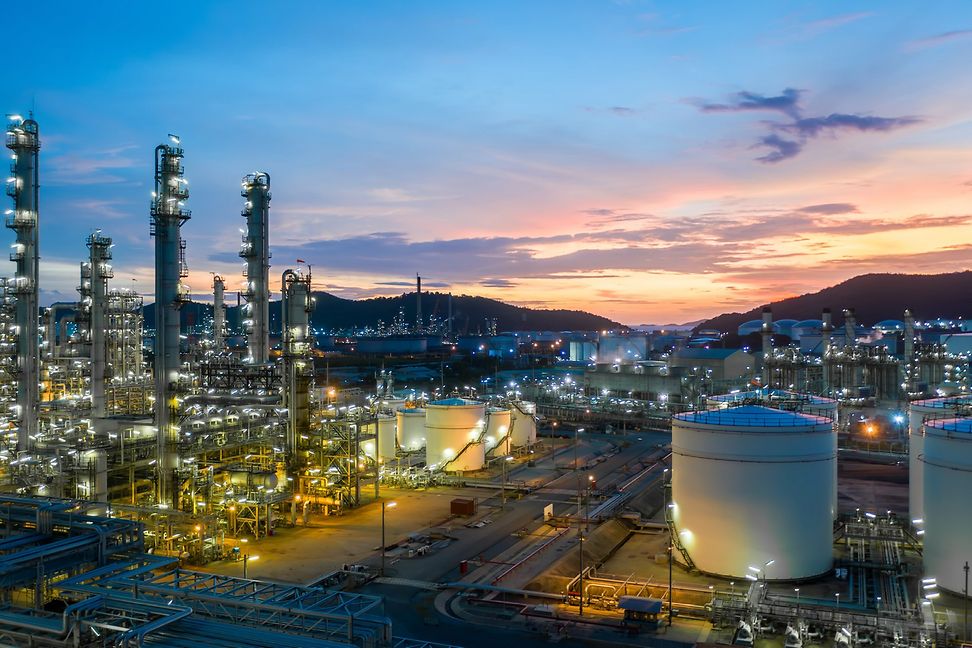 An industrial plant lit up at night against the skyline.