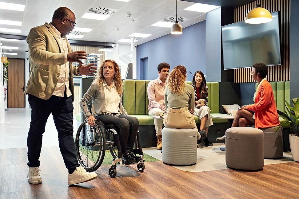 Various people meet in a relaxed working environment, including a woman in a wheelchair.