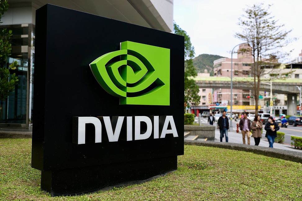 The Nvidia logo hangs in front of a building that people walk past.