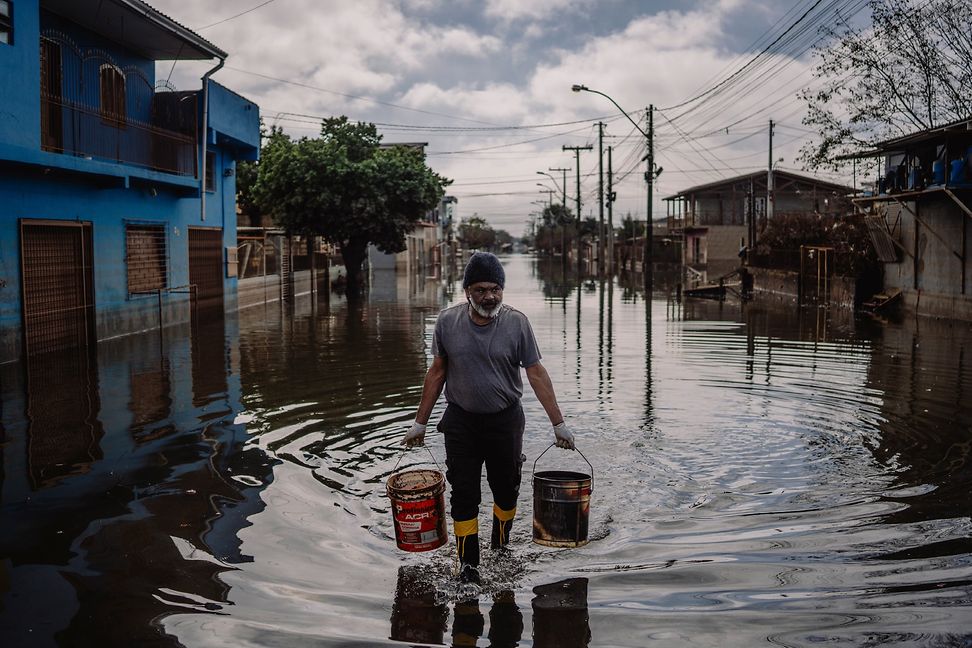 Flooded street in a village, man walks through the water