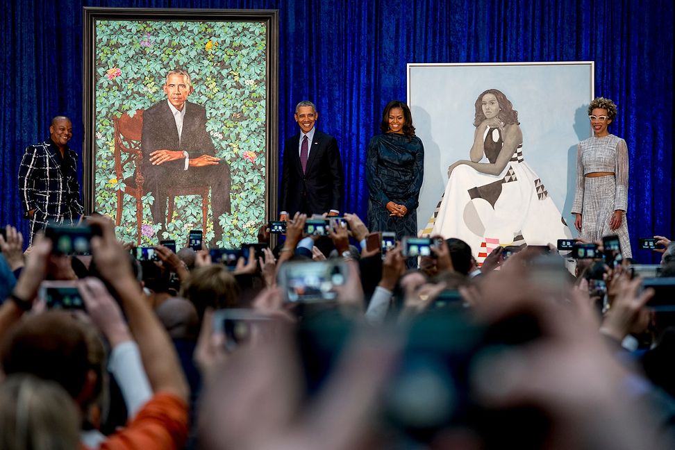 Barack Obama and Michelle Obama next to their portraits and artist Kehinde Wiley