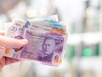 hand holds selection of British sterling notes