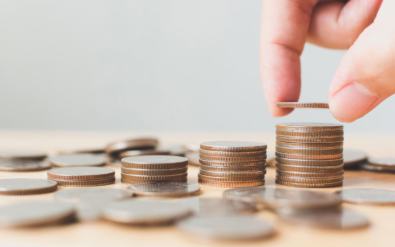 hand adds to ascending stacks of coins