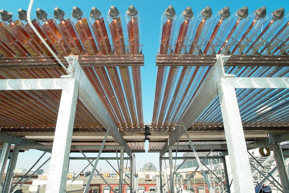 Vacuum tubes run along a metal structure. A city can be seen in the background.